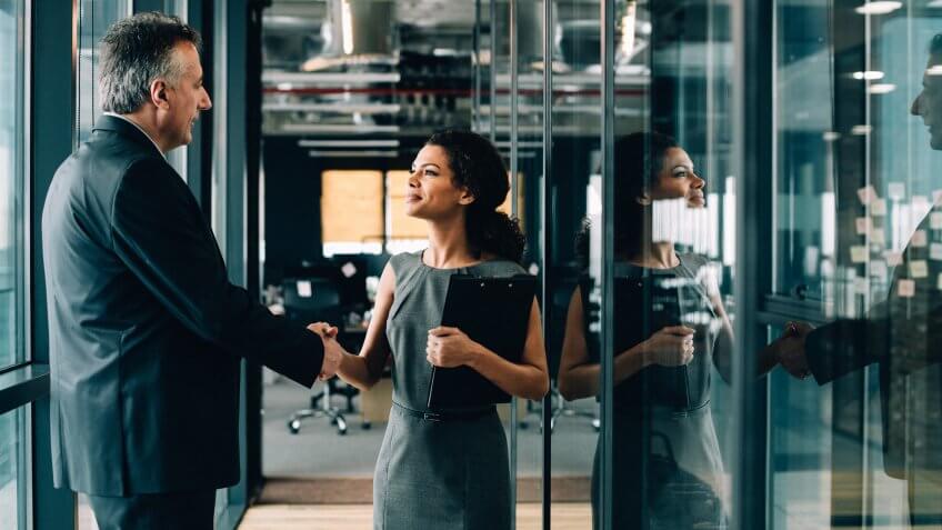 Businesswoman and businessman shaking hands in the office.