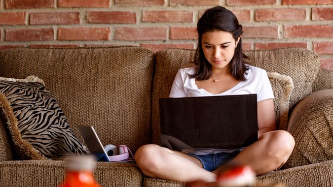 Spaanse jonge vrouw werken op een laptop computer thuis.