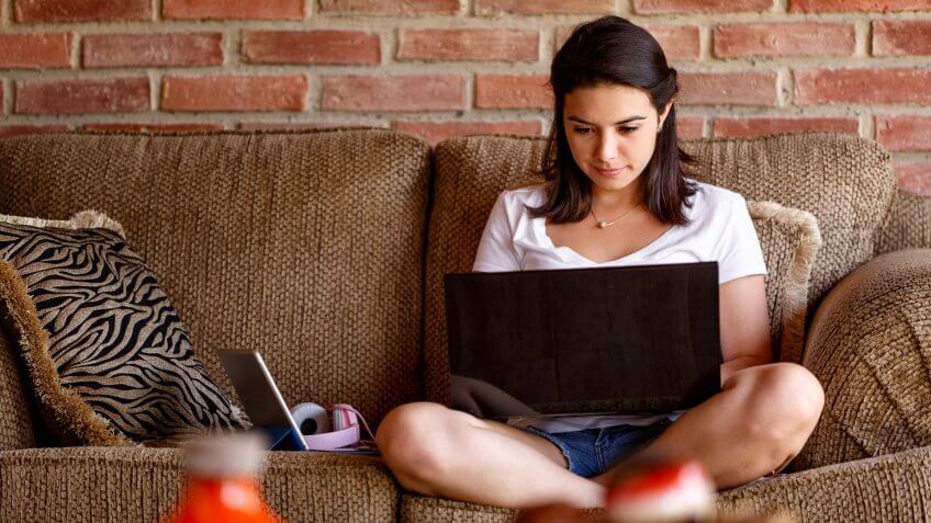 Hispanic young woman working on a laptop computer at home.
