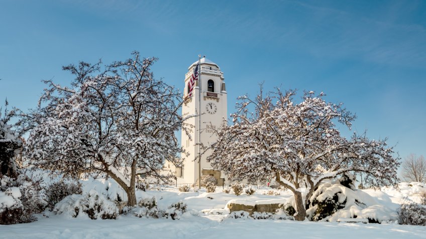 Snow covered city park with historic building.