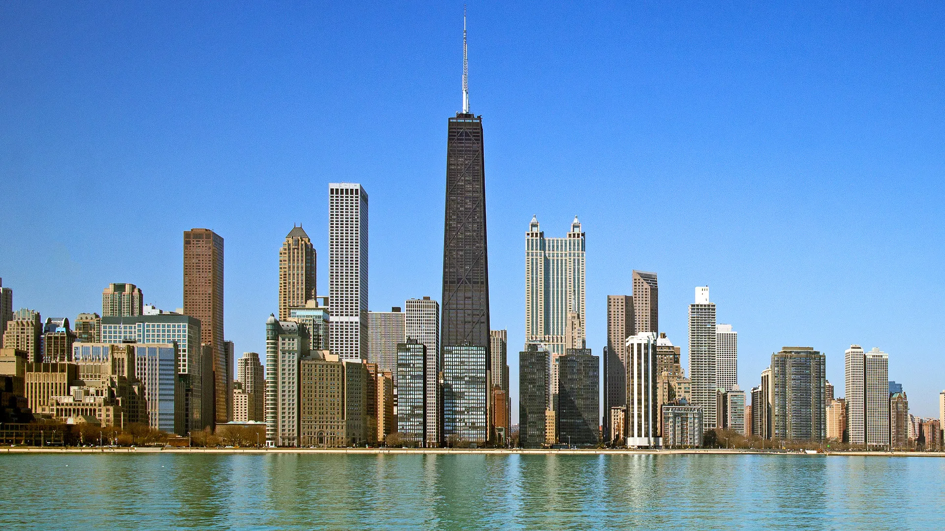 Day view of Chicago with buildings reflection on the water.