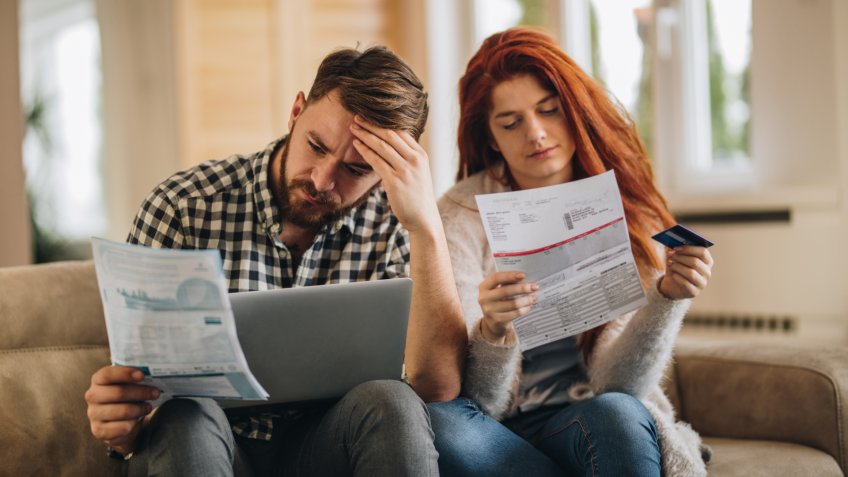 Worried couple feeling frustrated while have to pay their bills over Internet.
