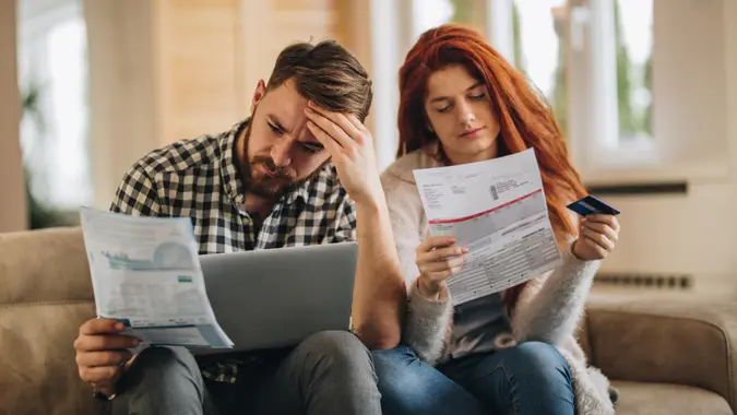 Worried couple feeling frustrated while have to pay their bills over Internet.