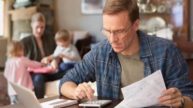 Father paying bills with family behind him