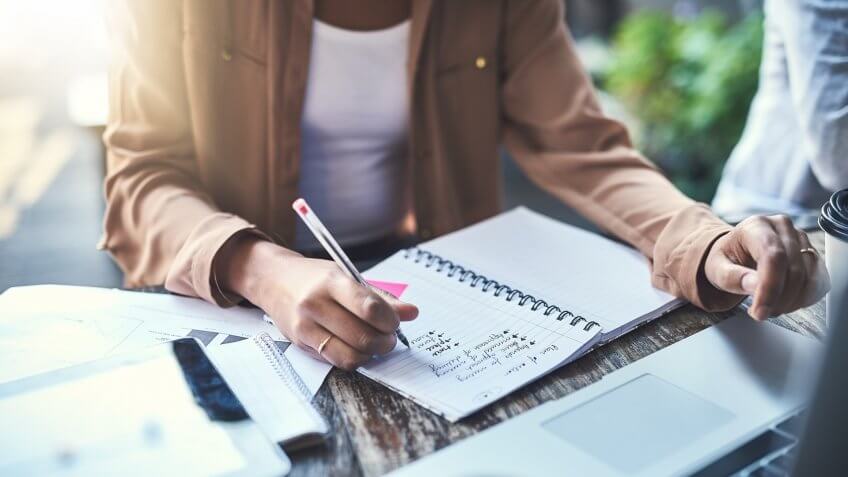 Closeup shot of an unrecognisable businesswoman writing notes at a coffee shop.
