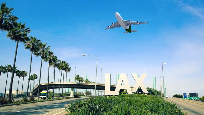 Los Angeles Airport sign full highway with airplane flying overhead.