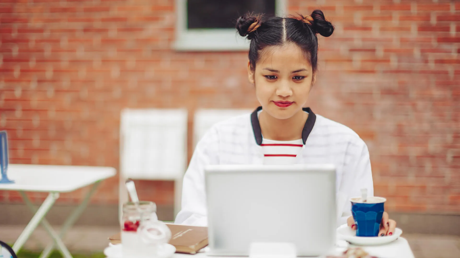 Millennial blogger working on laptop outside at a cafe