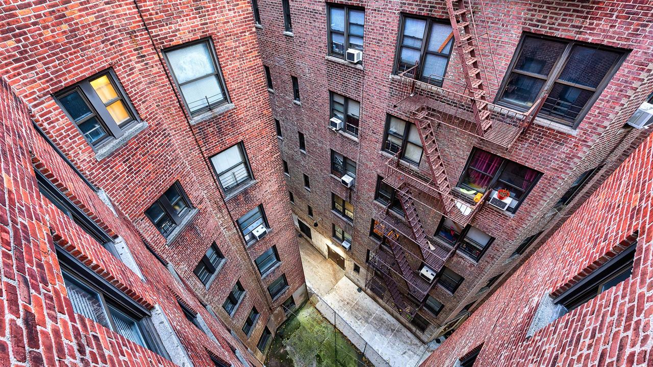 High angle, looking down view on illuminated brick apartment condo building architecture in Fordham Heights center, Bronx, NYC, Manhattan, New York City with fire escapes, windows.