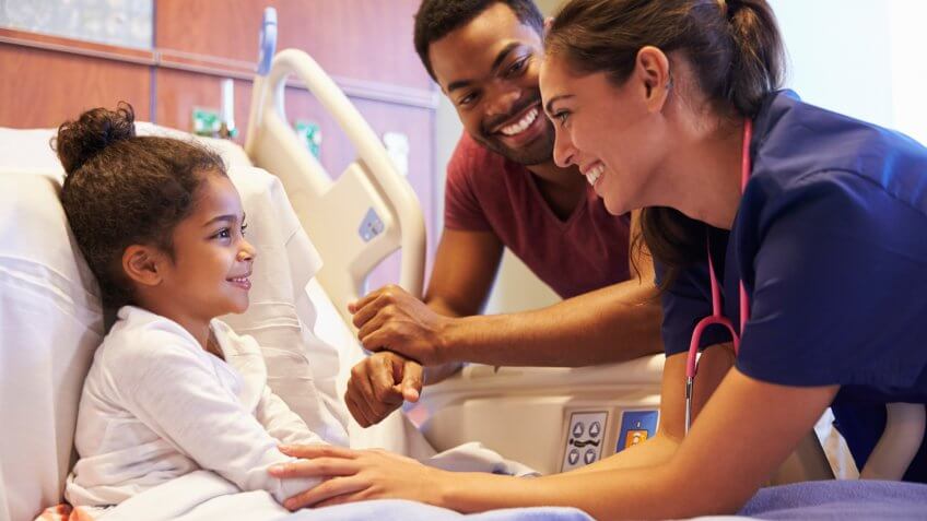 Pediatrician Visiting Father And Child In Hospital Bed