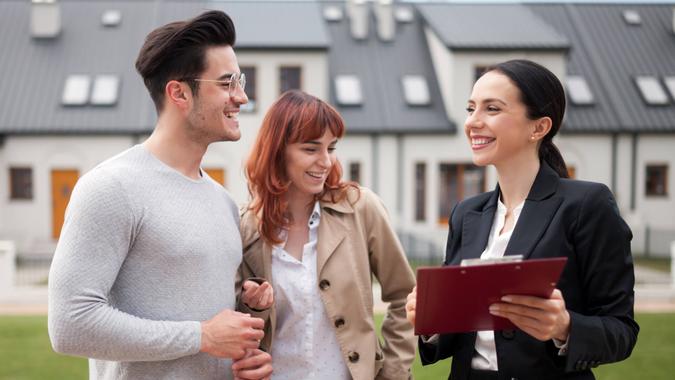 Real estate agent talking with young couple about buying new house