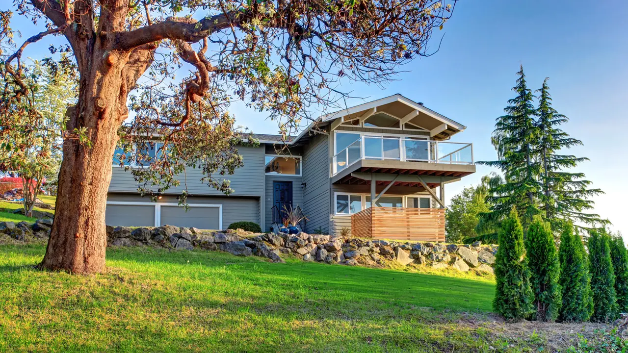 Two story house exterior with gray siding and natural stone landscape design