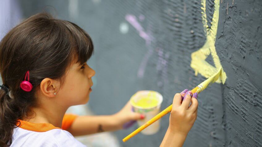 Young girl painting on wall mural