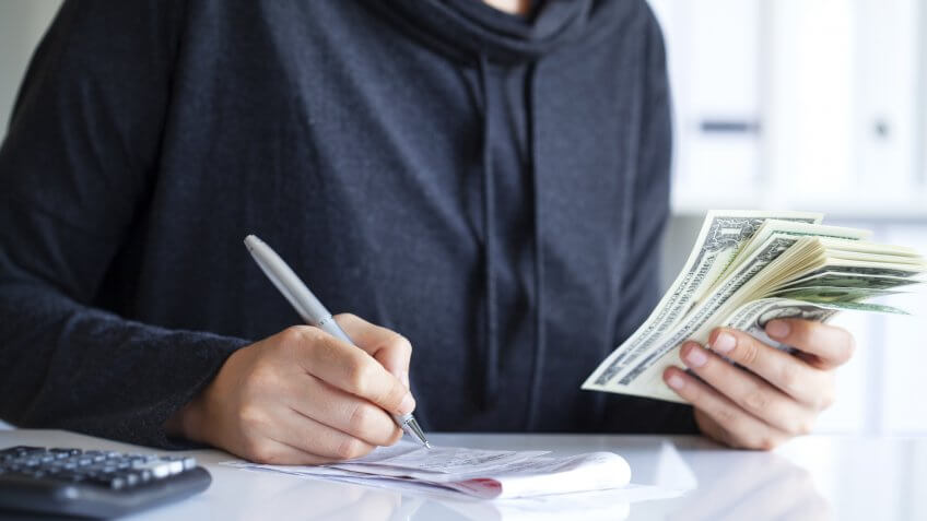Young woman counting money with calculator
