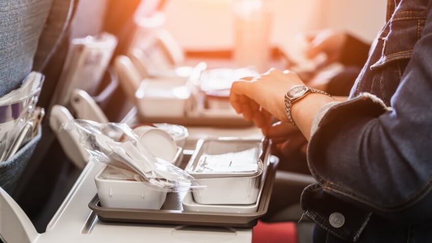 woman passengers eats lunch in travel aboard of international flight.