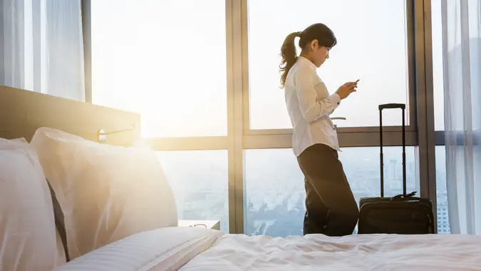 businesswoman texting on the phone , standing aganist the window, travelling in hotel, shanghai china.
