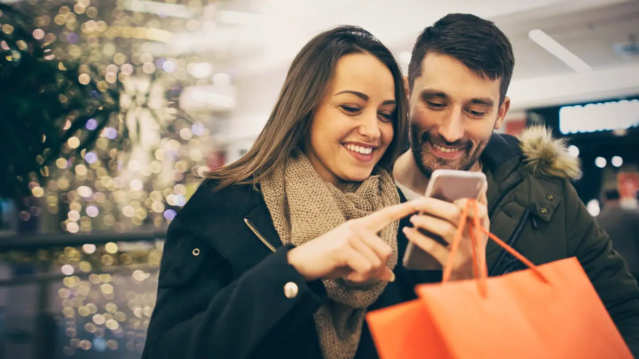 Happy couple shopping in the city with smartphone.