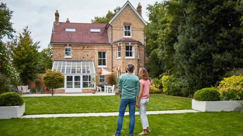 Rear view of mature couple looking at house.