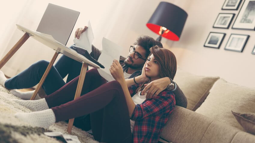 Young married couple doing their paperwork together, paying taxes online.
