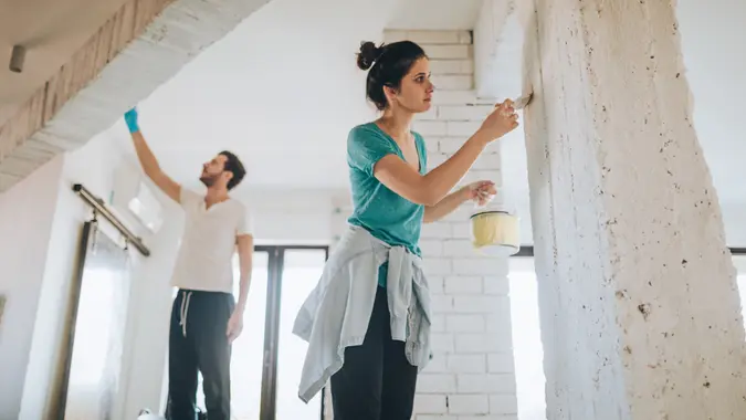 Young couple painting their living room.