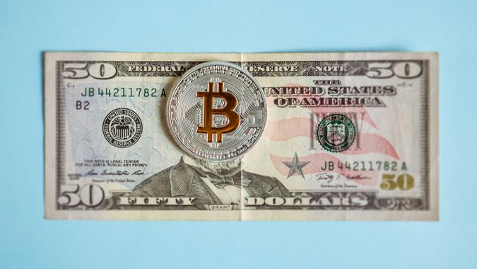 Krakow, Poland, November 1, 2018, Bitcoin lies on dollars covering a portrait of the American President, the concept of the victory of cryptocurrency over paper money.