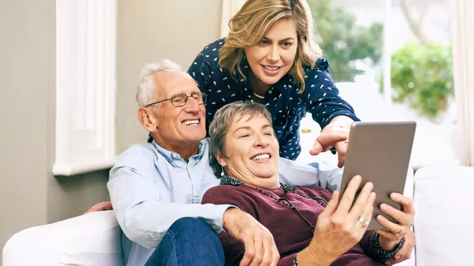 Shot of an adult daughter and her senior parents using a tablet together at home.