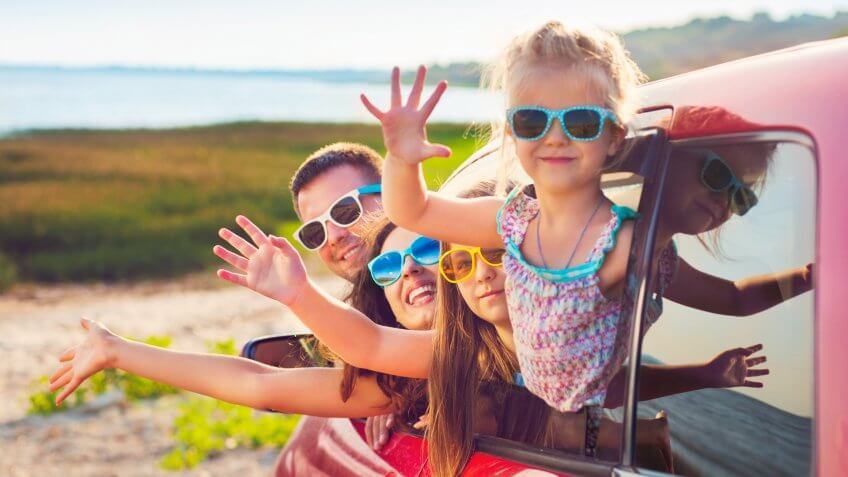 Portrait of a smiling family with two children at beach in the car.