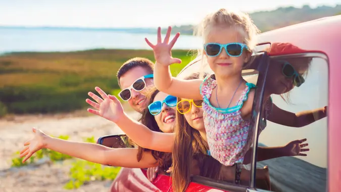Portrait of a smiling family with two children at beach in the car.