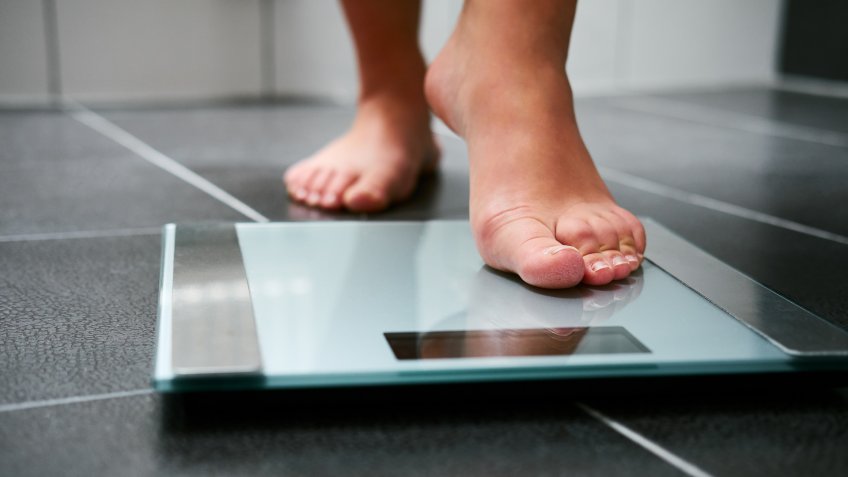 Female bare feet with weight scale in the bathroom.