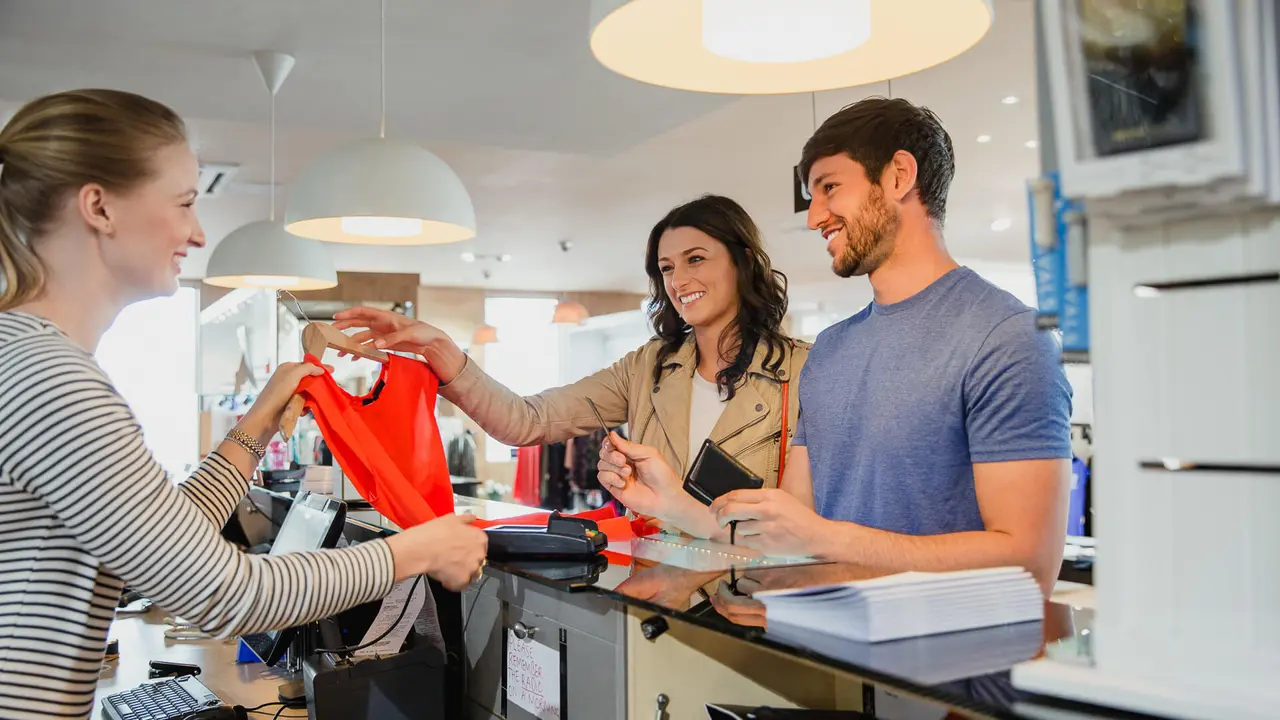 A couple shopping in an exclusive fashion clothing store, using their credit card to buy new clothes.