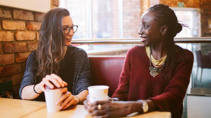 Portrait of a two young women of different ethnicities having a coffee after work, talking, laughing, having a fun time together.