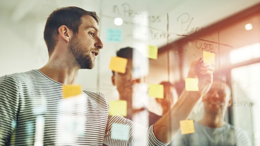 Cropped shot of a group of young designers using sticky notes during a brainstorming session.