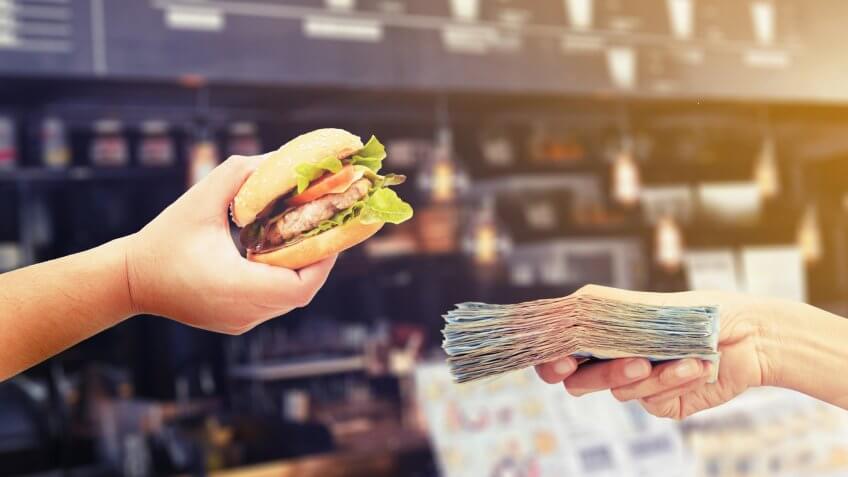hands holding burger and cash