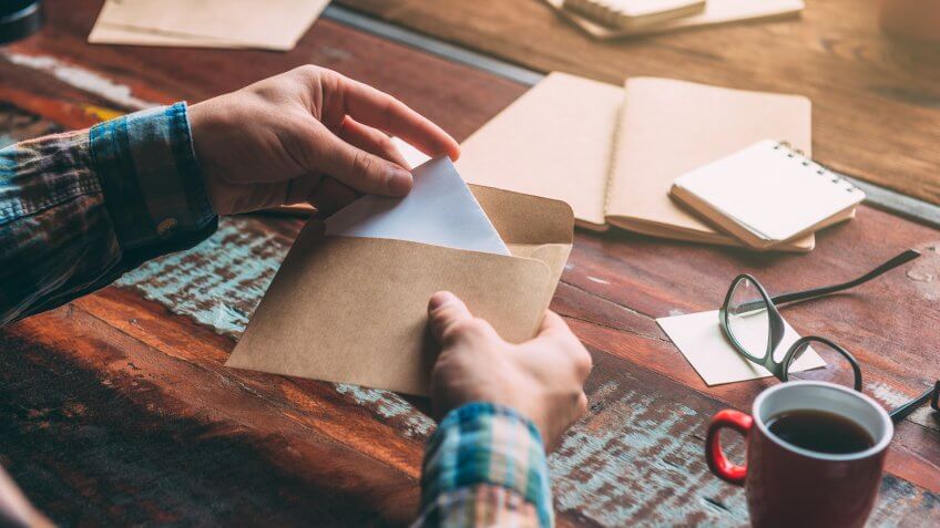 man inserting donation in an envelope while sitting at the rustic wooden table