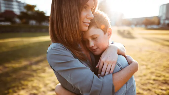 teenager embraced with mom consoling her son.