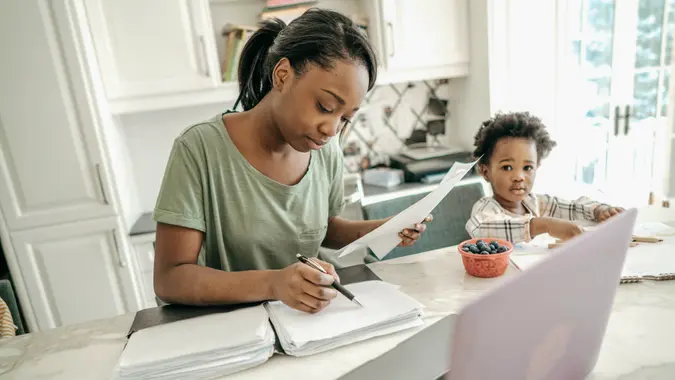 Mom making computation with her daughter beside her.