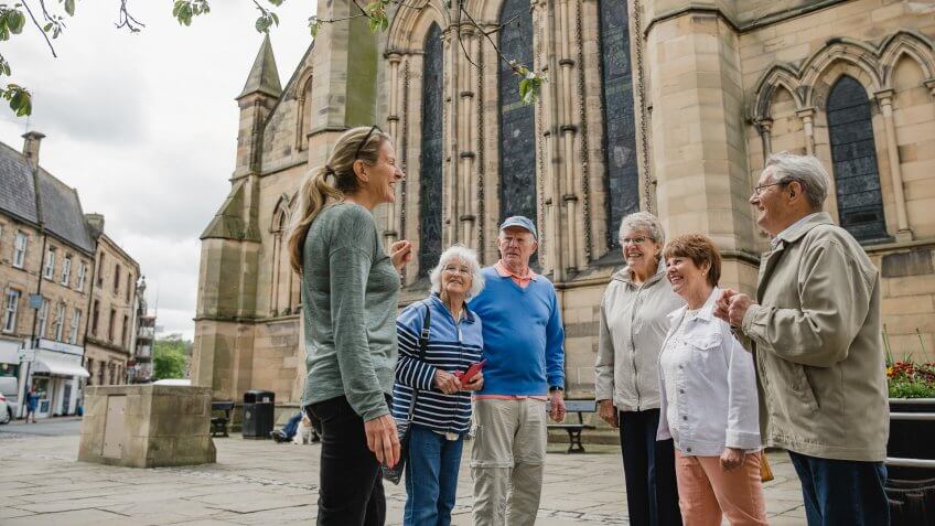 Senior group are doing a local tour in Northumberland with a guide.