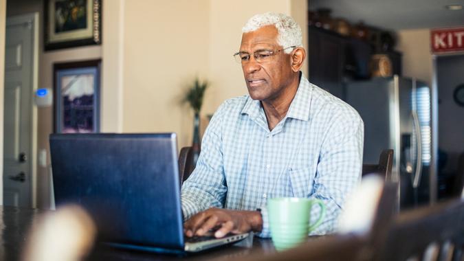 Senior Black Man Working on Laptop Computer at Home A senior black man works from his computer at home.