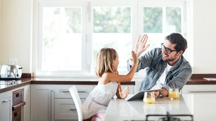 Shot of an adorable little girl using a digital tablet with her father at home.