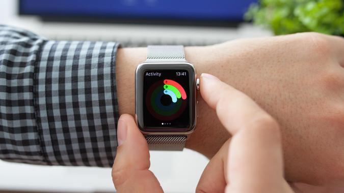 Alushta, Russia - August 11, 2015: Man hand with Apple Watch with app Activity on the screen and Macbook.