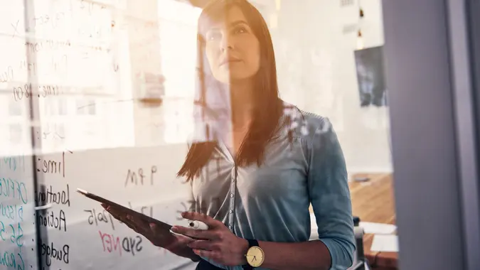 Shot of woman reading notes on a glass wall in an officehttp://195.