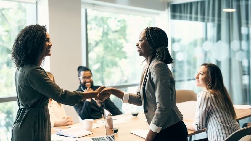 Shot of two young businesswomen shaking hands after a successful business meeting in the office at work during the day.