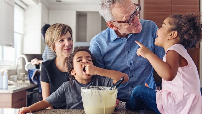 Grandparents making cupcake with kids.