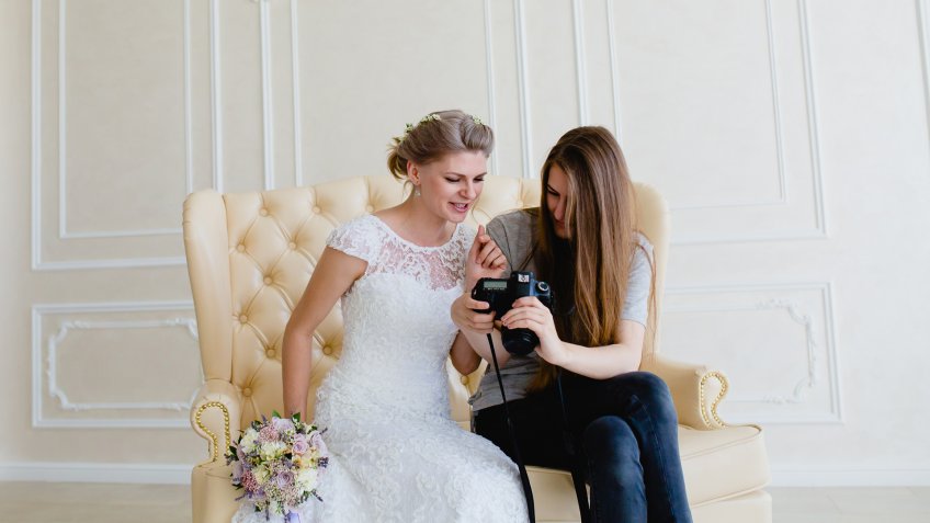Photographer with long hair shows the young sexy bride had just taken photos.