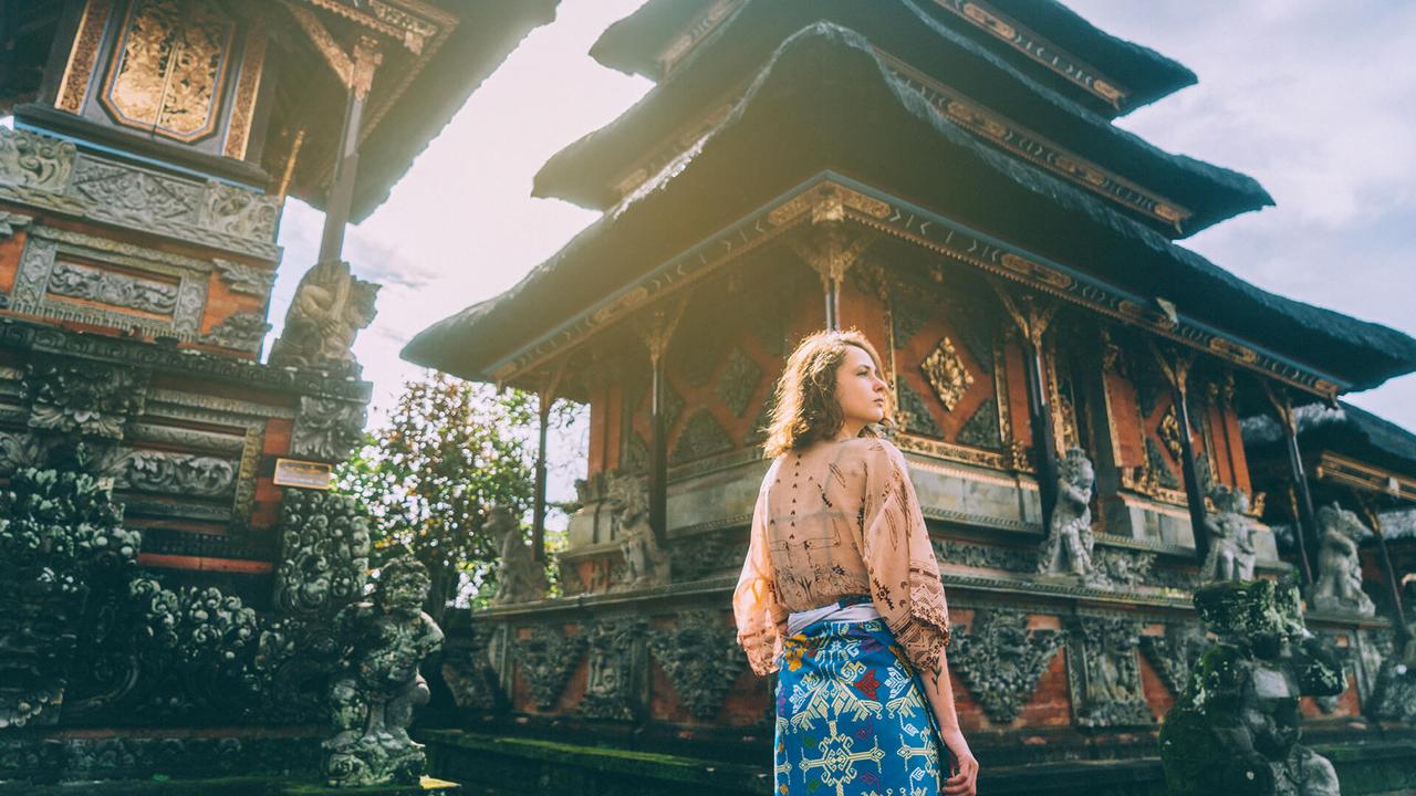 Young Caucasian woman walking in Balinese temple, Indonesia.