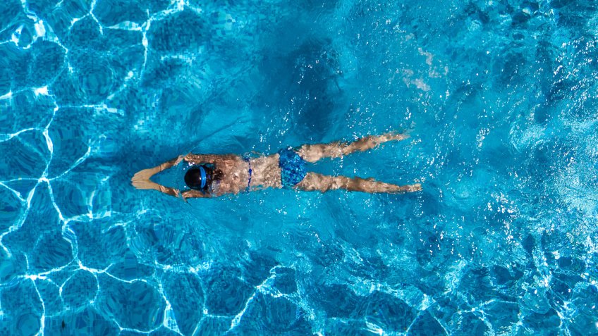 Aerial top view of woman in swimming pool water from above, tropical vacation holaday concept.