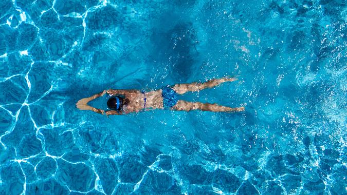 Aerial top view of woman in swimming pool water from above, tropical vacation holaday concept.