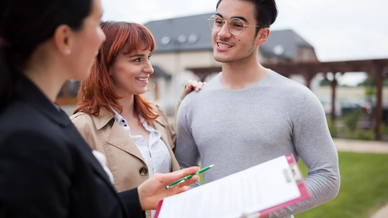 Real estate agent consulting young couple about buying new home.