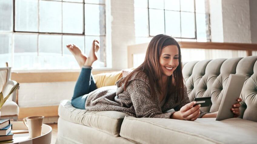 Shot of a young woman doing some online shopping while relaxing on her sofa.