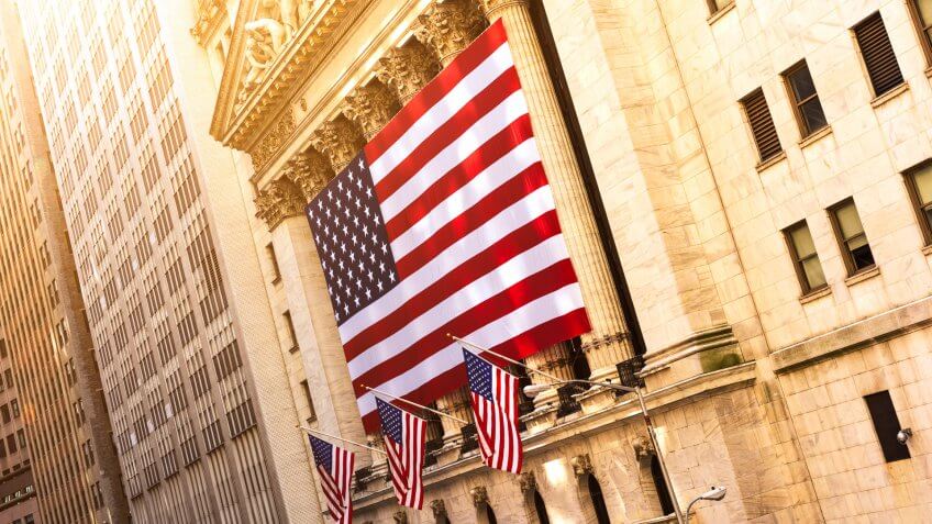 Famous Wall street and the building in New York, New York Stock Exchange with patriot flag.