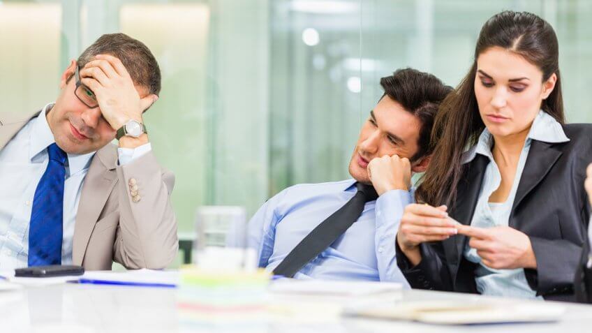 Tired and bored business people sitting in the office.